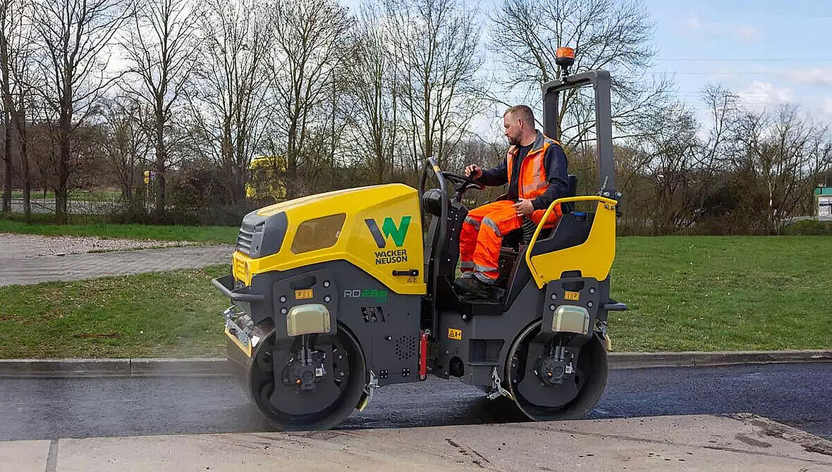 Elektryczny walec tandemowy Wacker Neuson RD28e podczas zagęszczania nawierzchni przy krawężniku.