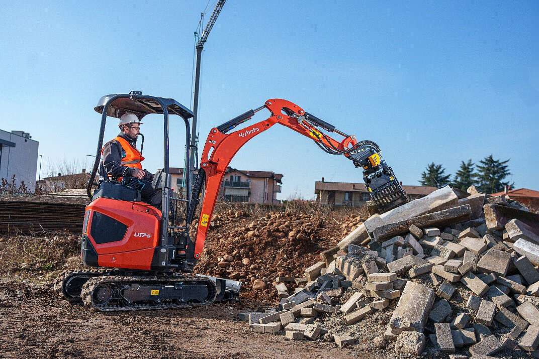 Kubota U17-5 z chwytakiem podczas porządkowania elementów betonowych.